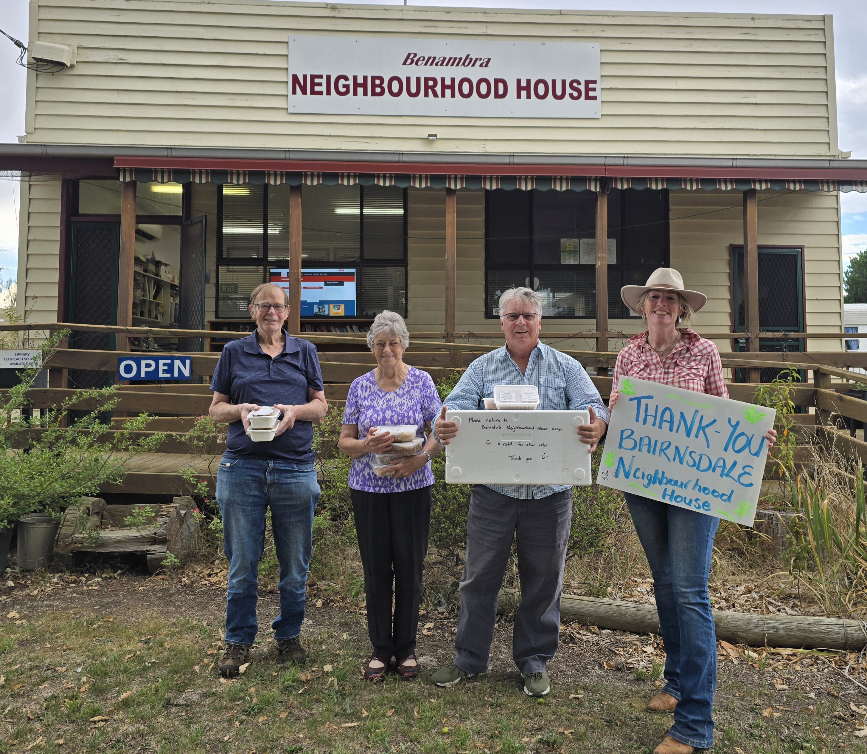 People standing outside Benambra Neighbourhood House holding frozen food boxes and thanking Bairnsdale Neighbourhood House