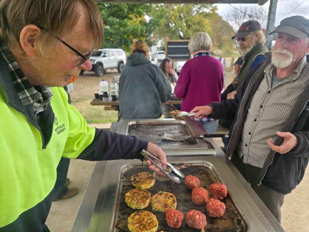 People cooking a barbeque in the park outside Benambra Neighbourhood House